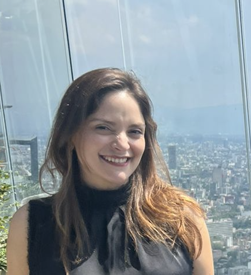 Paola del Bosque smiling in front of a panoramic city view